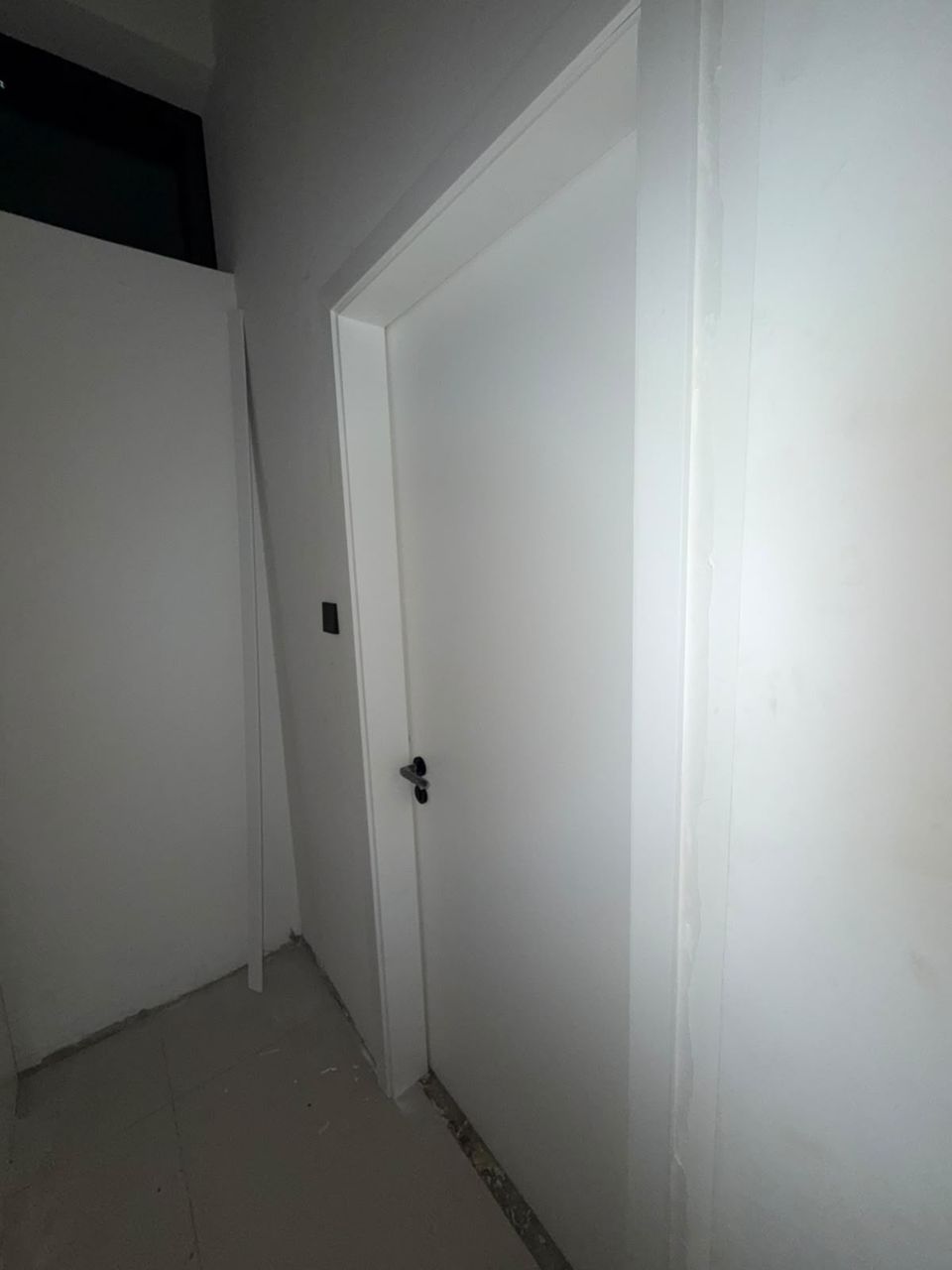 White flush hidden door with black lever, Meydan District One