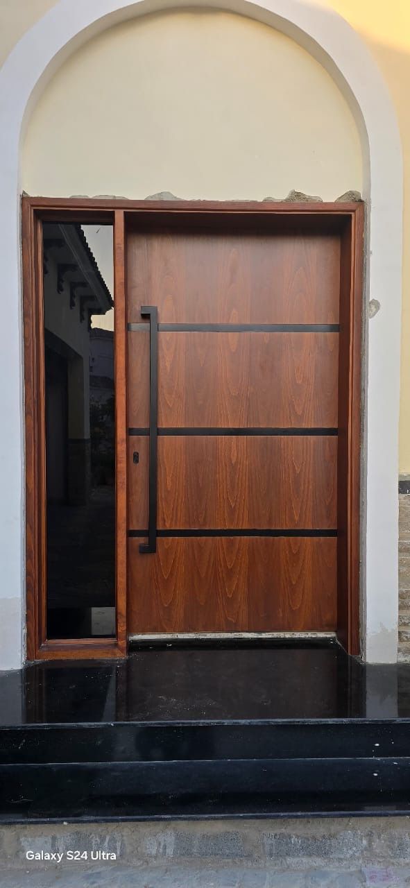 Mahogany entrance door with black inlay bars and sidelight under an arch, Jumeirah Golf Estates