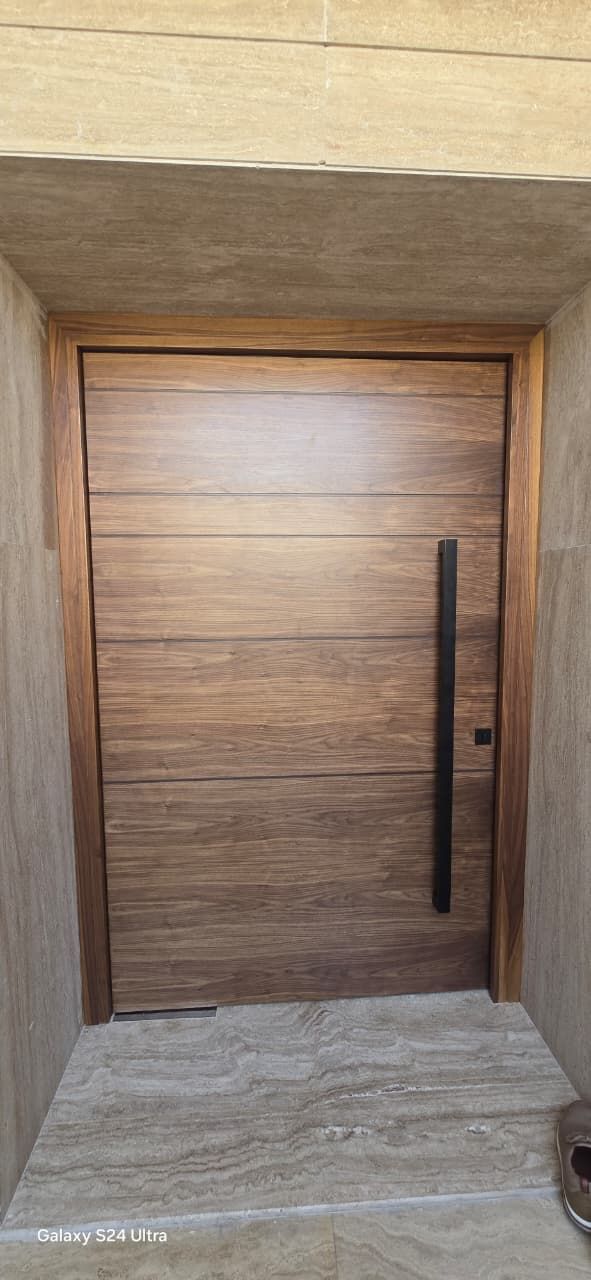 Walnut grooved pivot door in a travertine portal, Jumeirah