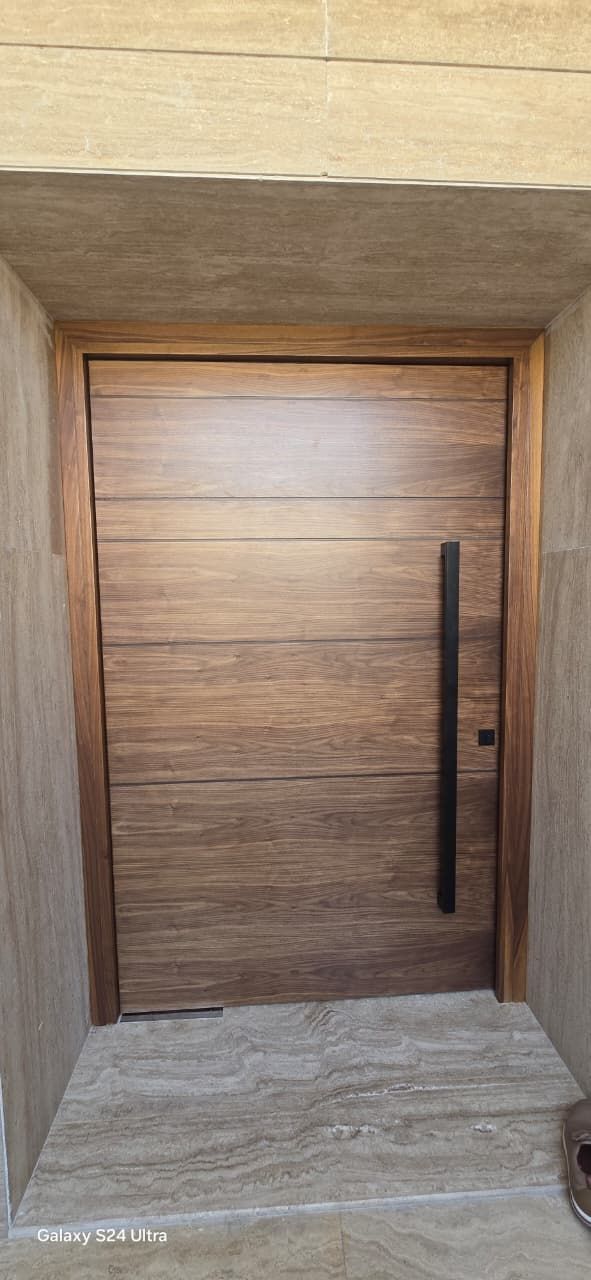 Walnut pivot door with black pull, travertine surround, Jumeirah