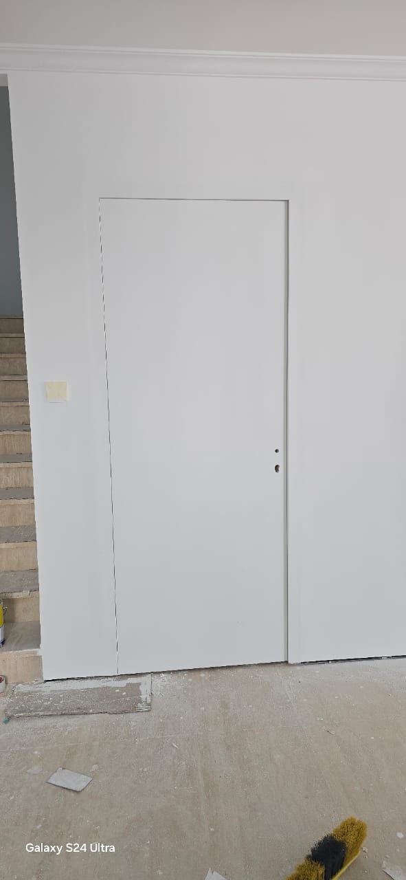 Hidden door frame plastered flush with the wall