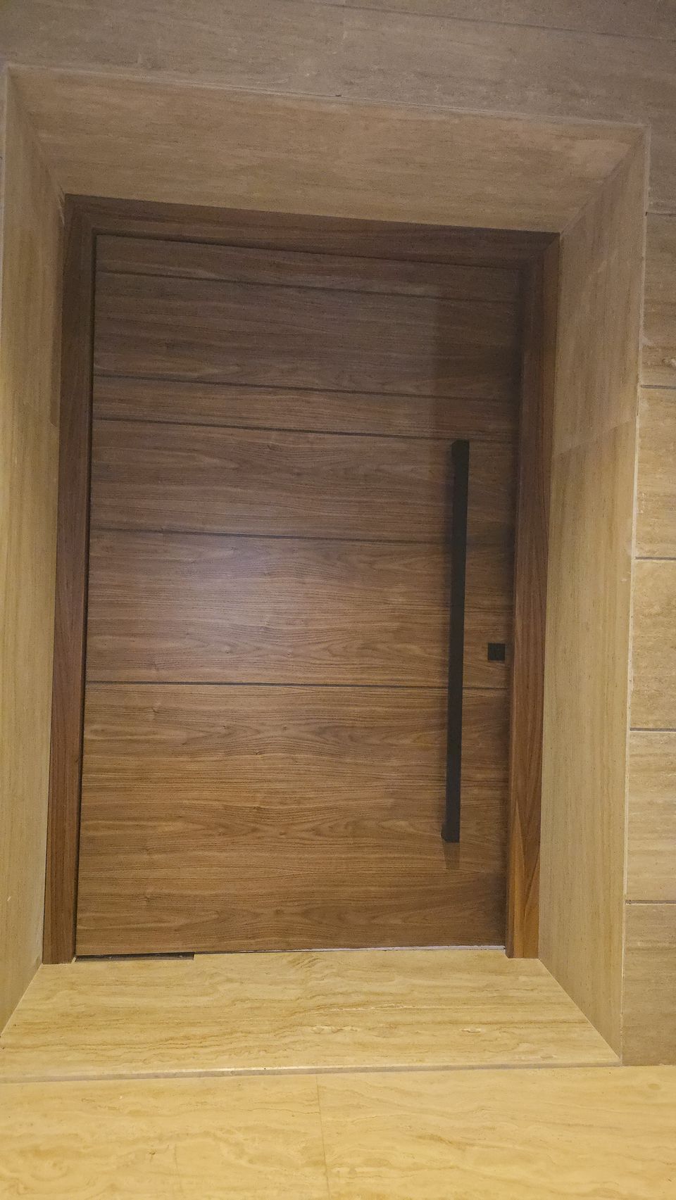 Walnut Grooved Pivot Door In Travertine Surround
